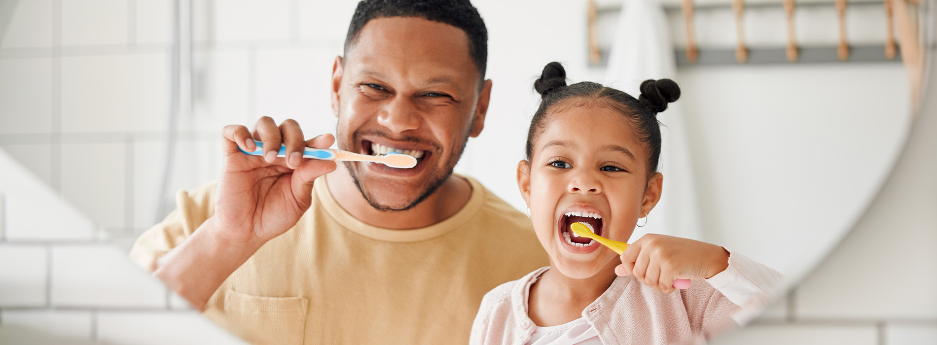 A man and child are brushing their teeth together in front of a white oven.