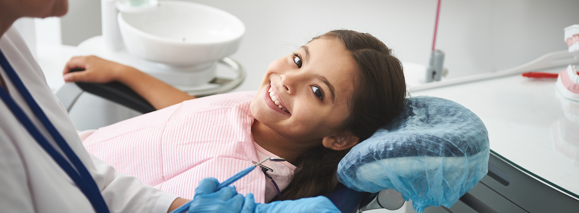 Woman sitting in dental chair with blue mask over her mouth.