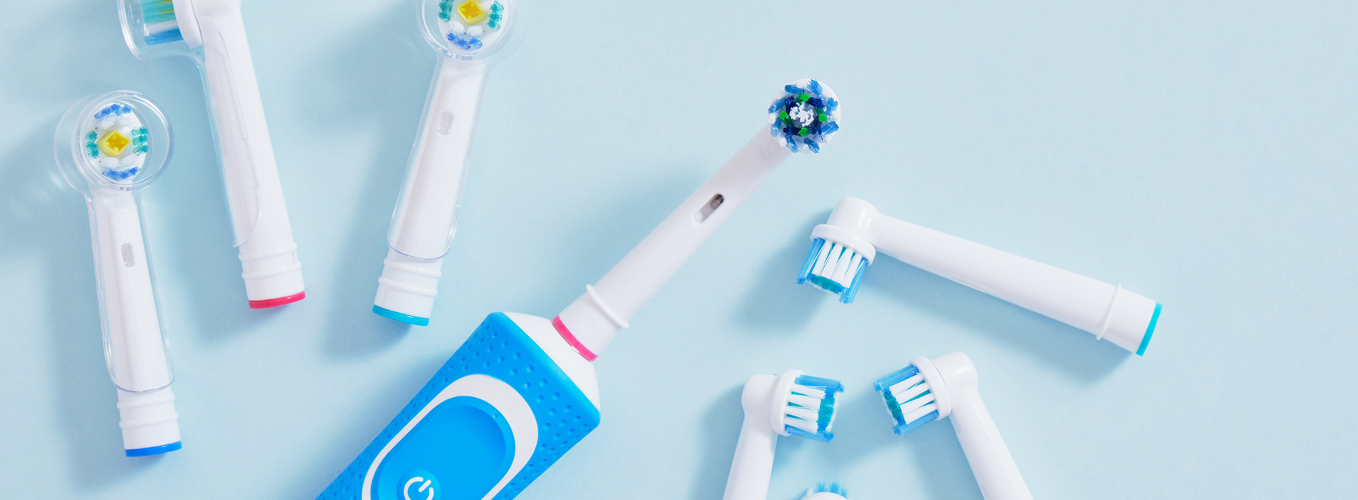 The image shows a collection of toothbrushes with various colors and designs scattered on a surface, likely for sale or display purposes.